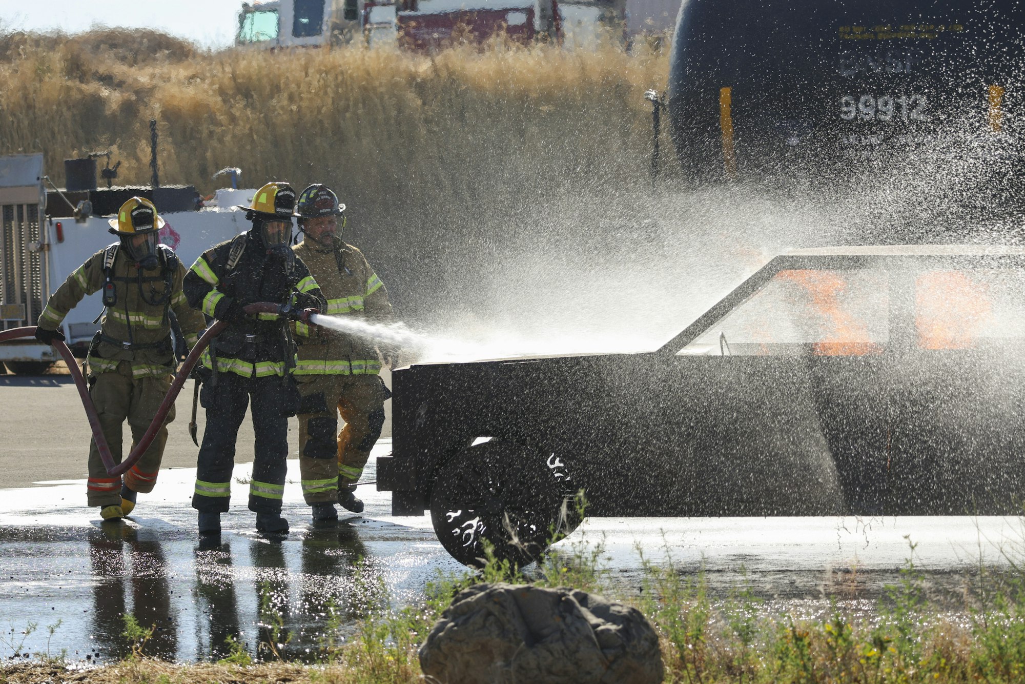 Firefighters use a hose to extinguish a fire on a vehicle.