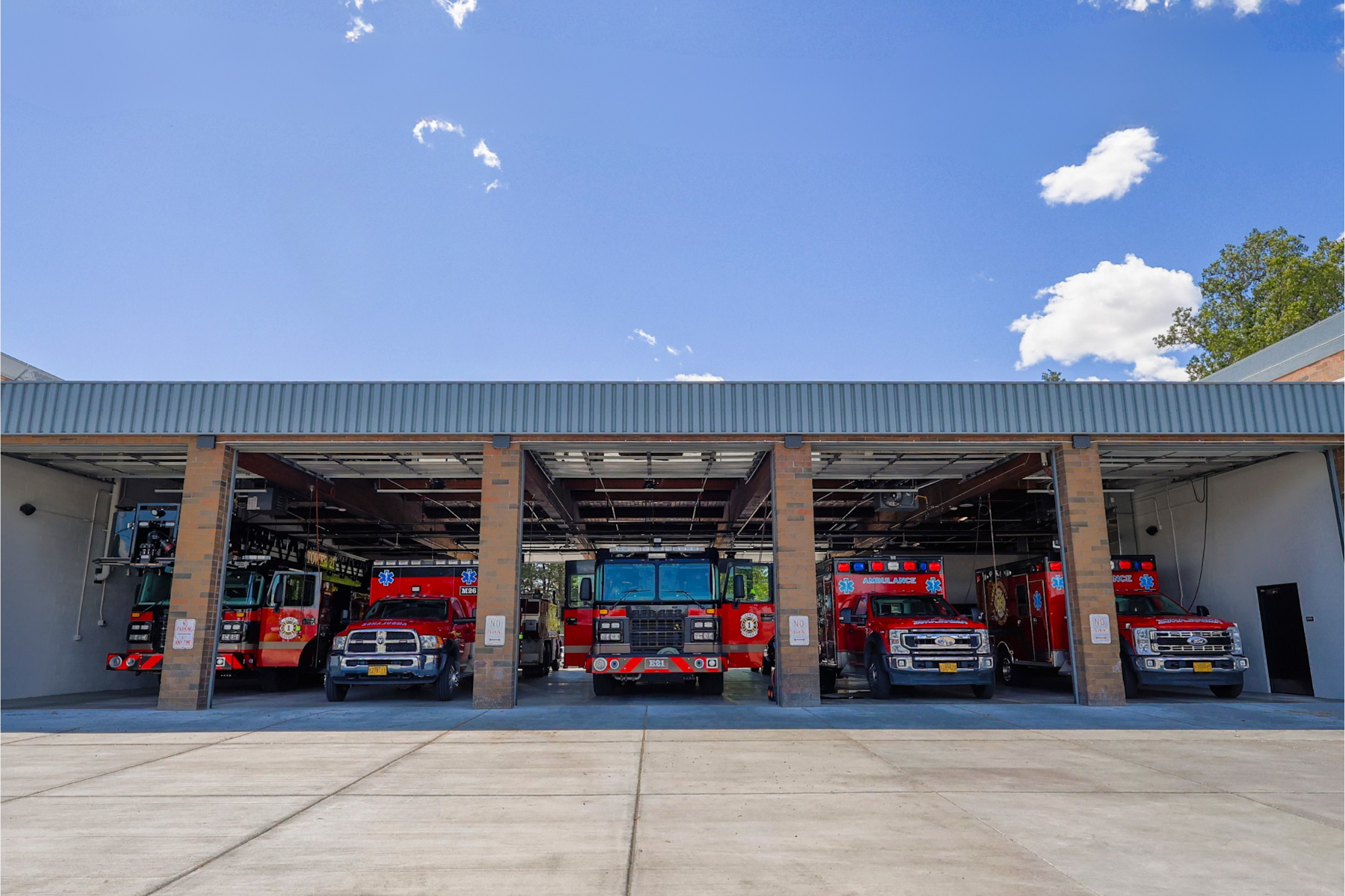 The image shows a fire station with multiple emergency vehicles, including fire trucks and ambulances, parked inside.