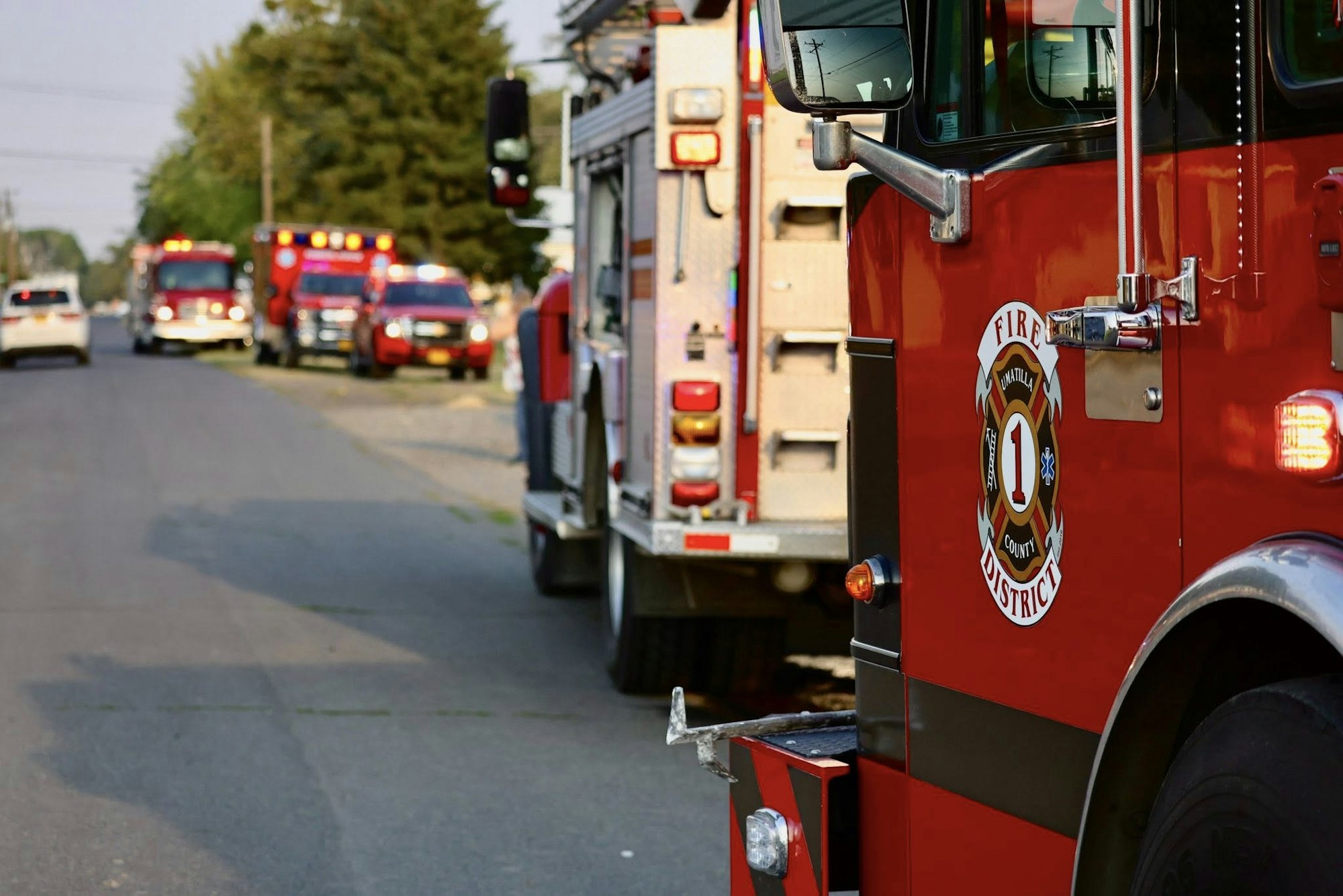 Firetruck and emergency vehicles on a street, emergency lights on.