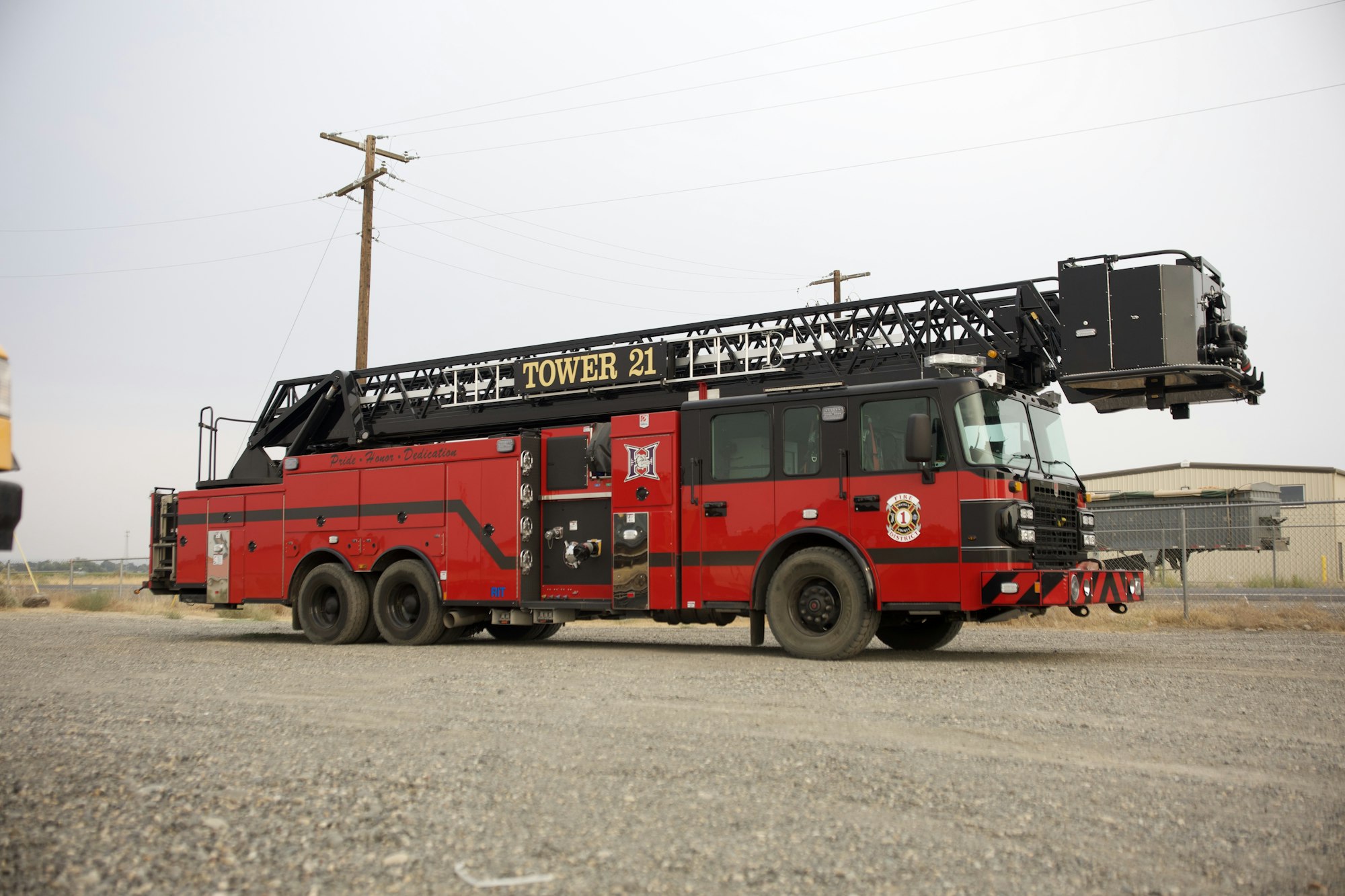 A red fire truck labeled "Tower 21" with an extended ladder in a parking area.