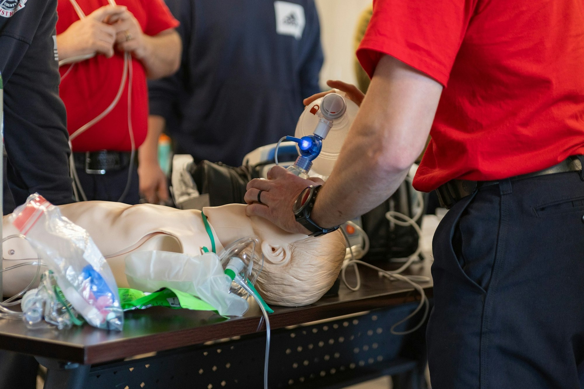 CPR training with a manikin and medical personnel using a bag valve mask for resuscitation practice.