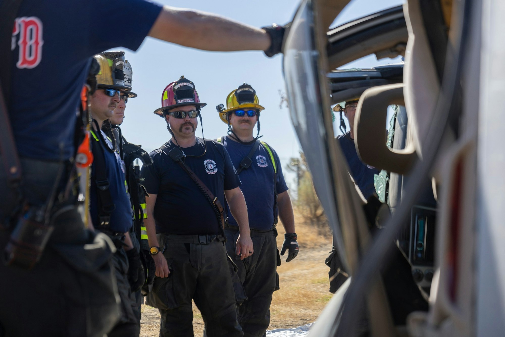 Firefighters standing next to a vehicle, observing or assessing a situation.