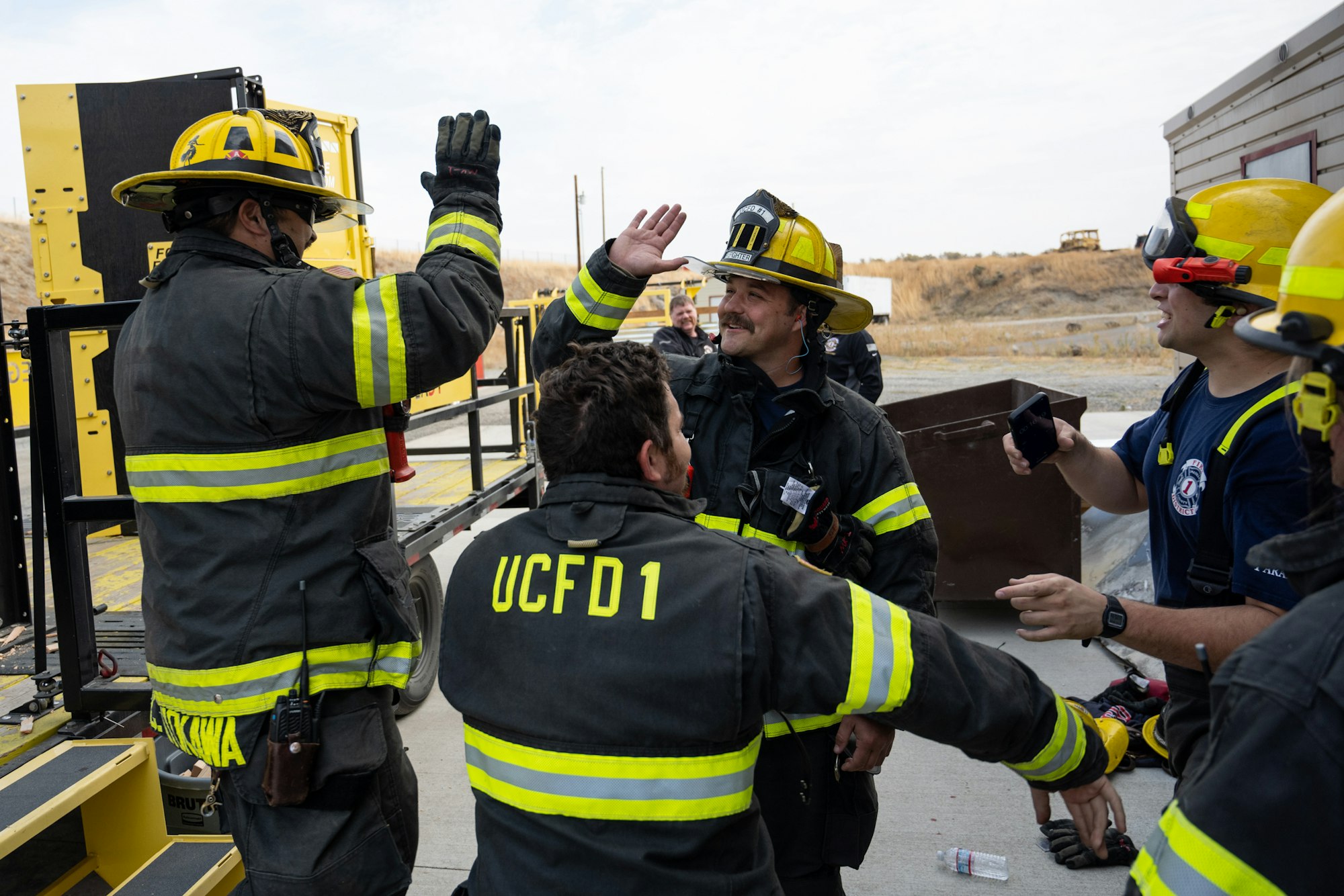 Firefighters celebrating with high-fives in full gear.