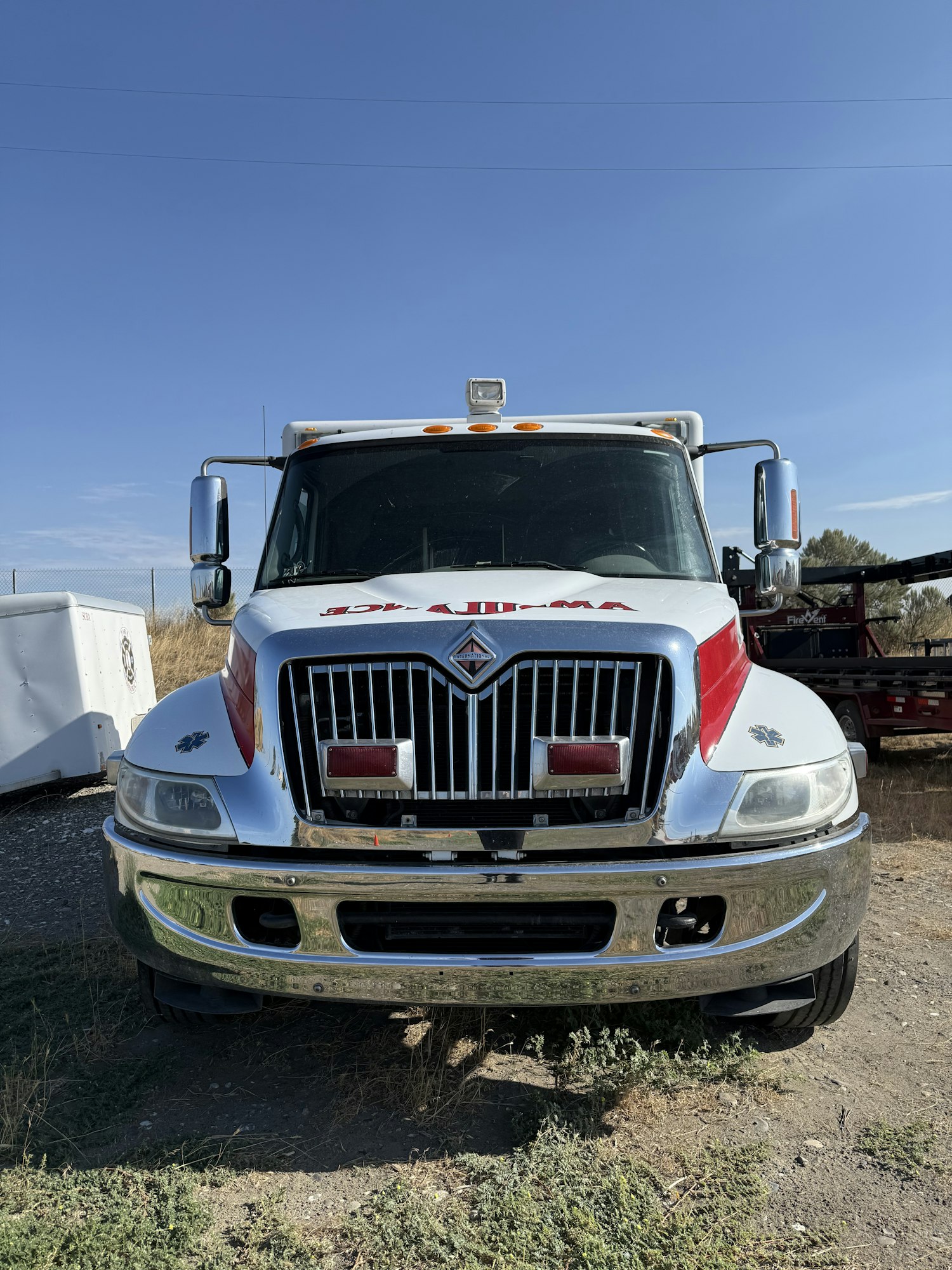 Front view of a white tow truck with "Salvage" written on it, parked on a dirt surface under a clear blue sky.