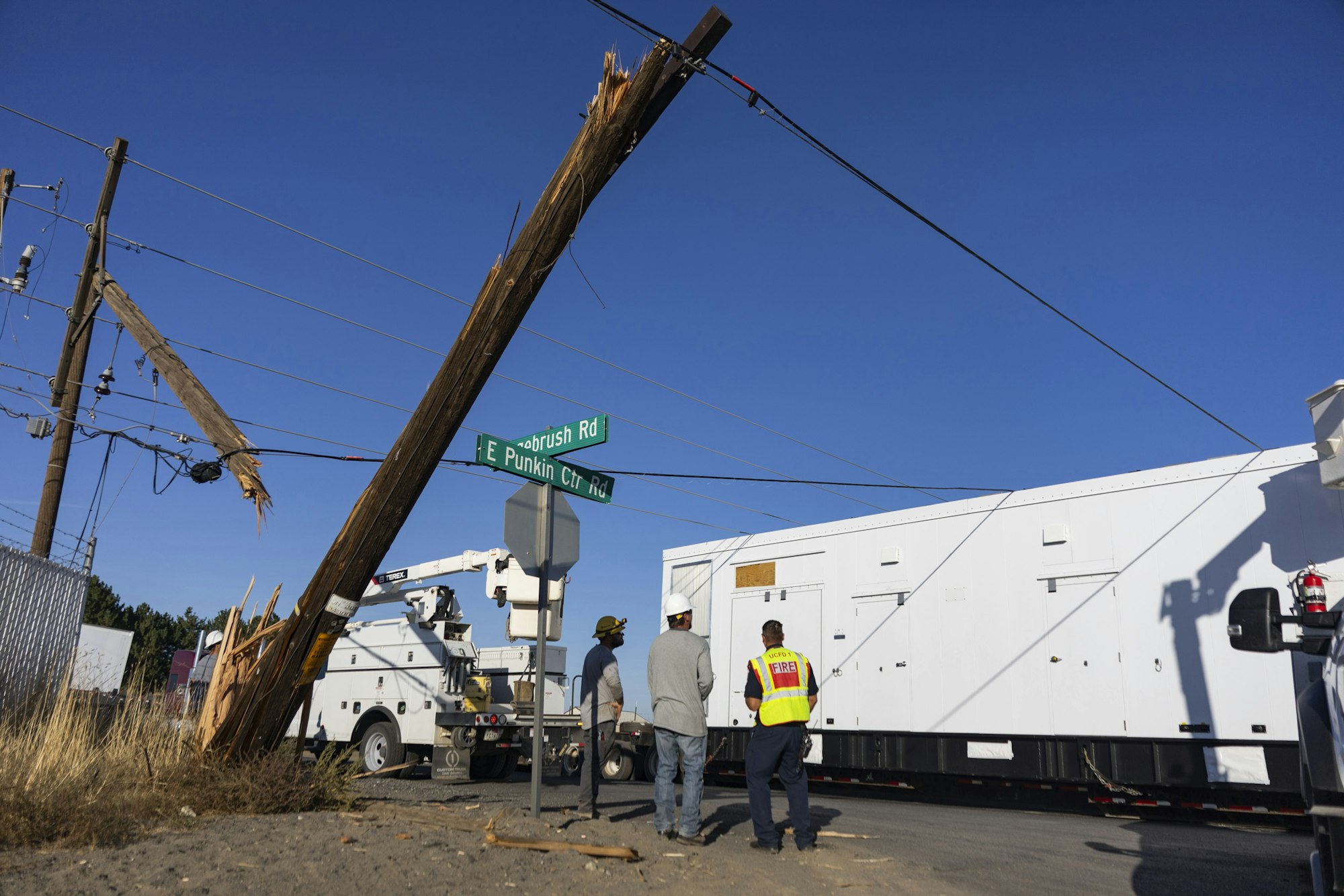 Damaged utility pole near Seabush Rd, workers and truck at site.