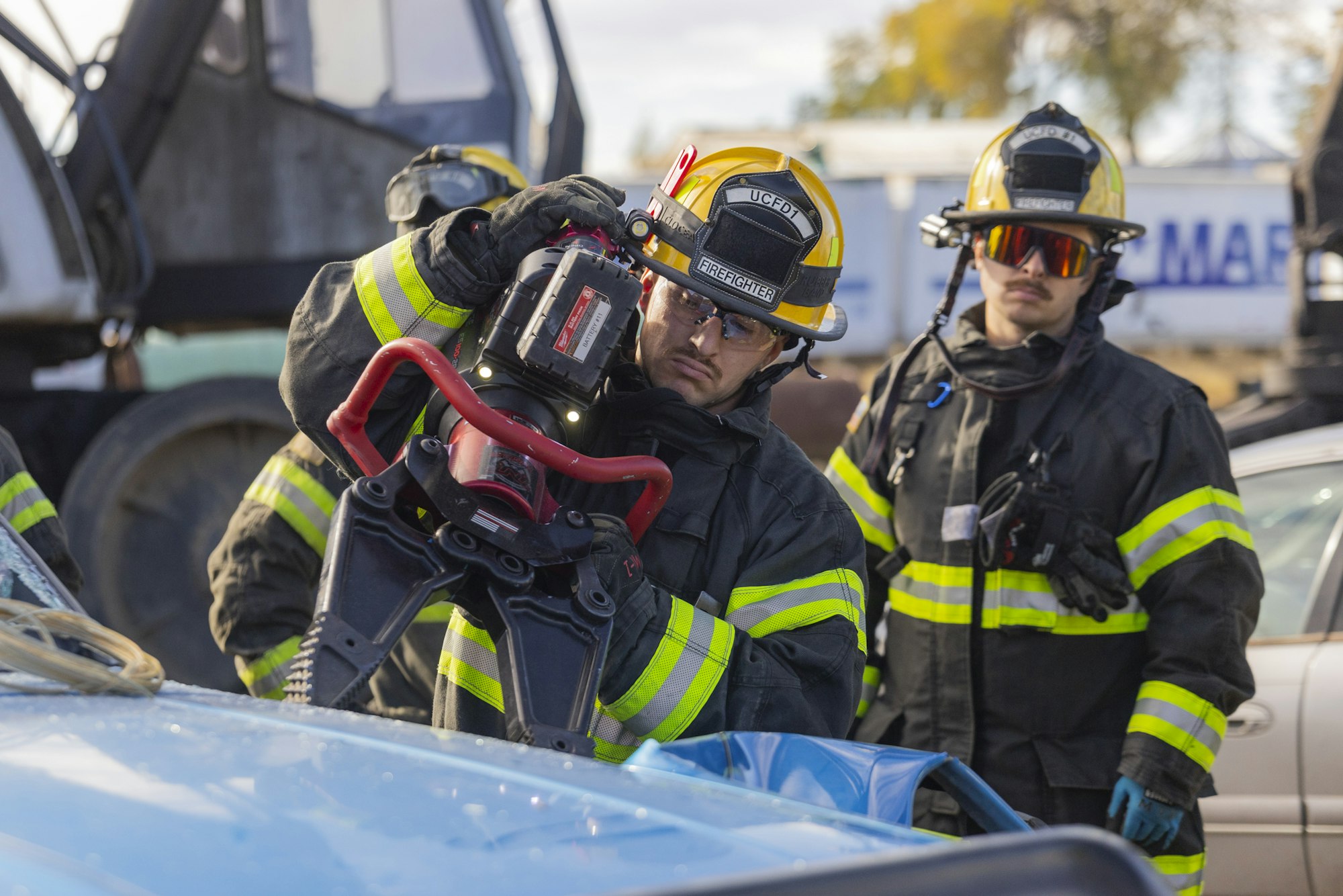 Firefighters using hydraulic rescue tool on a vehicle.