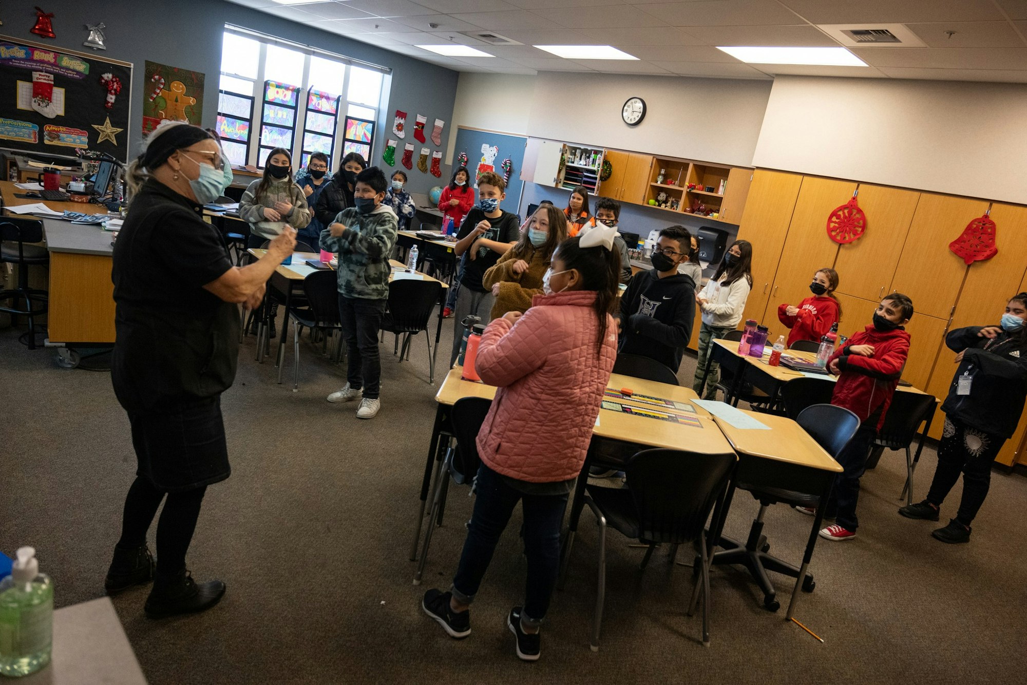 A teacher and masked students participate in a classroom activity.