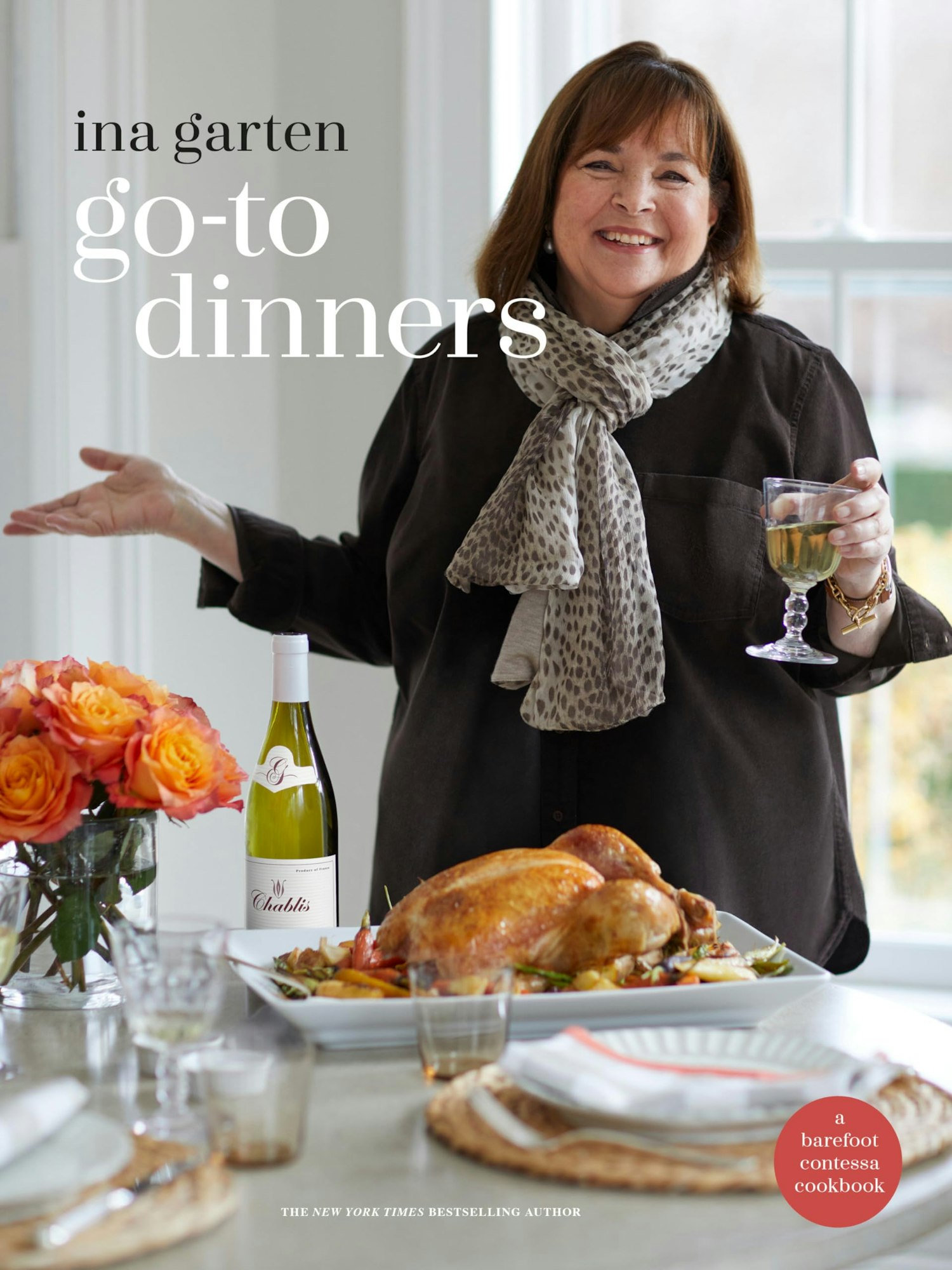 A cookbook cover featuring Ina Garten, a roast chicken, wine, and roses. Title: "Go-To Dinners."