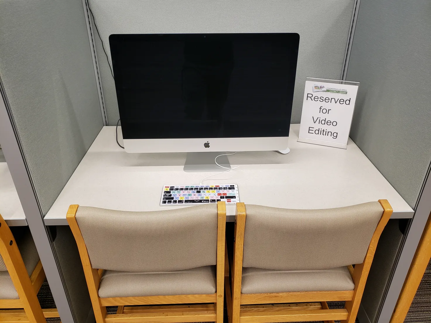 A computer workstation with a sign indicating it's reserved for video editing.