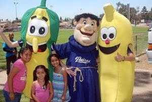 Group photo with kids and people in vegetable and banana costumes, plus a bearded character in a blue robe.