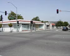 An empty street corner with a small commercial building and traffic lights.