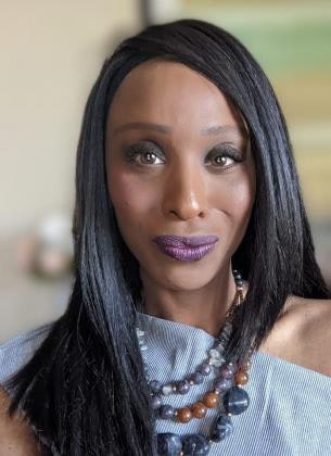 A person with long black hair, makeup, and a beaded necklace.
