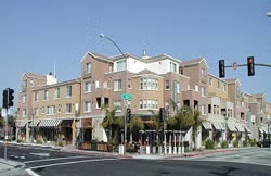 A multi-story building with shops at street level on a city corner, featuring awnings and a streetlight.