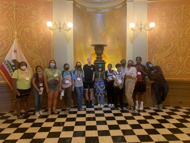 A group of people in a decorated room with checkered floor and a California flag.