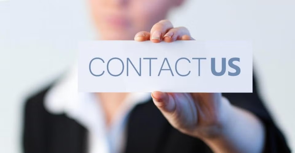 A person holds a sign that says "CONTACT US".