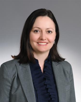 A professional portrait of a smiling woman in a suit with a ruffled blouse.