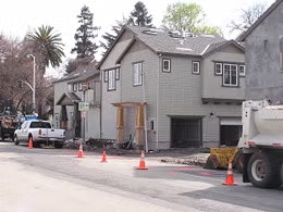 A residential area with houses, parked trucks, and traffic cones on the street.