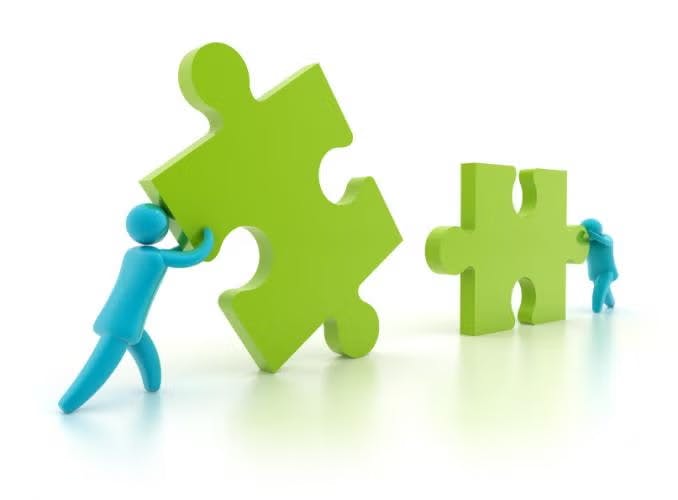 Two blue figures pushing large green puzzle pieces.
