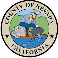 A logo for Nevada County, California, depicting a person panning for gold by a river, surrounded by a circular border.