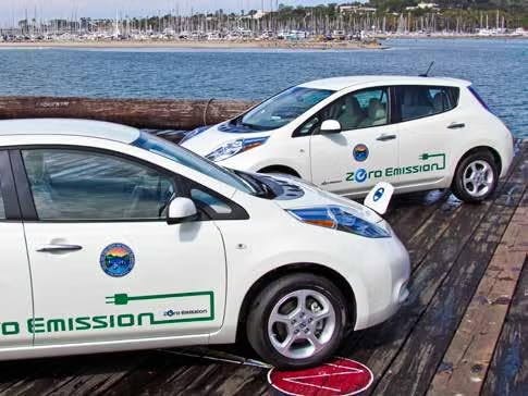 Two white electric cars labeled "Zero Emission" parked near a waterfront.