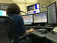 Person at a multi-monitor workstation, possibly within a control room or operations center.