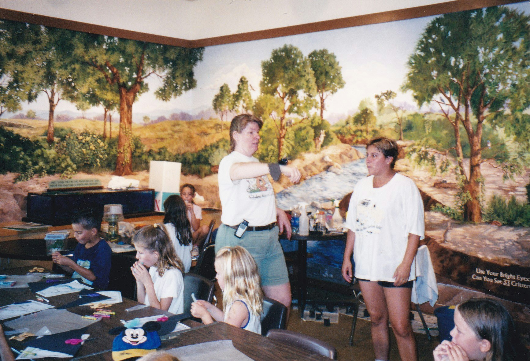 Children and adults in a room with a nature mural, engaging in crafts or activities.