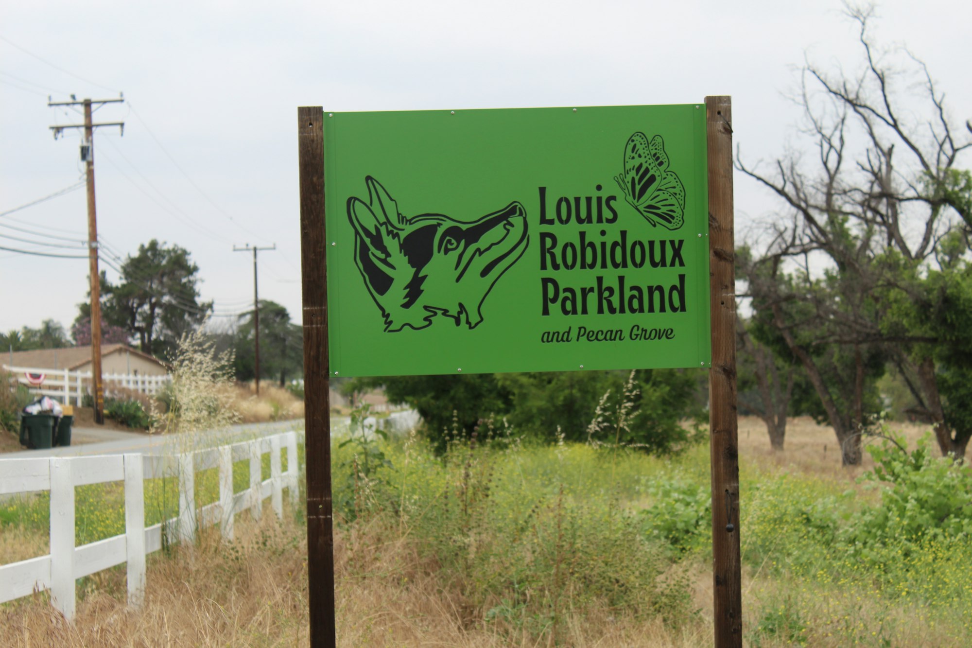 Sign for Louis Robidoux Parkland and Pecan Grove with a wolf and butterfly illustration.