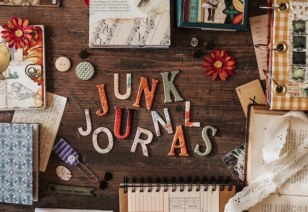 An artsy flat lay featuring the words "Junk Journals" with colorful letters, decorative items, and various journal materials.