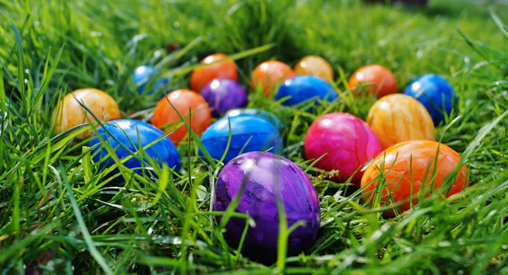 A colorful array of painted Easter eggs resting in green grass.