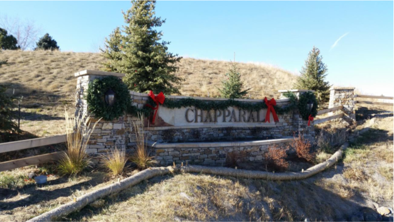 Stone entrance sign for "CHAPPARAL" adorned with holiday wreaths and red bows.
