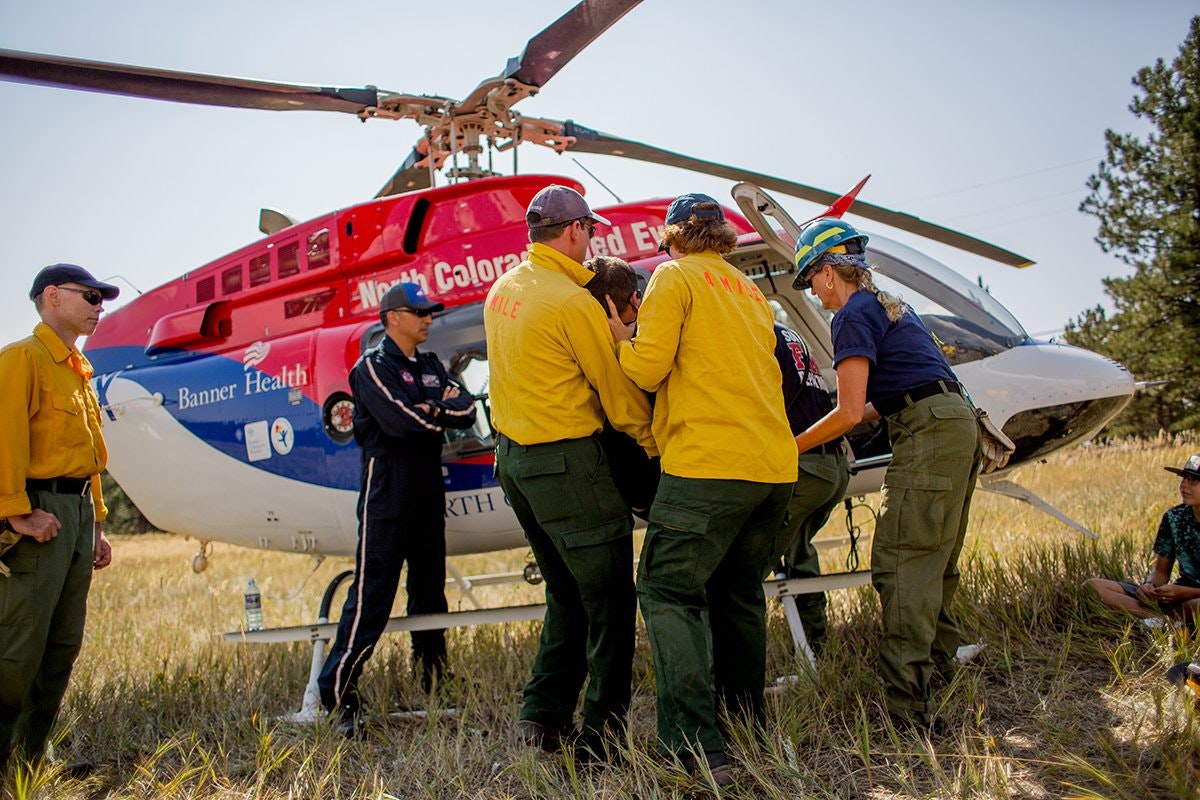 Medical team and firefighters load a patient into a helicopter for evacuation.
