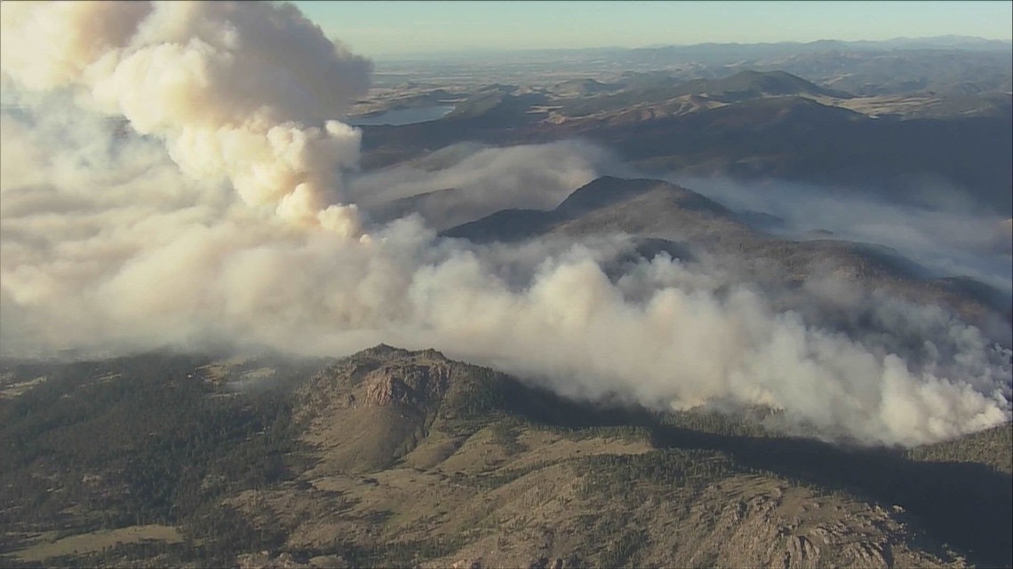 Aerial view of a large wildfire, with smoke covering mountainous terrain.