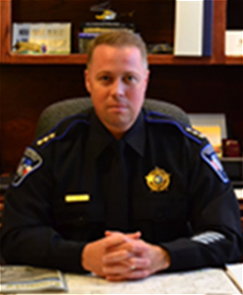 A person in police uniform sitting at a desk.