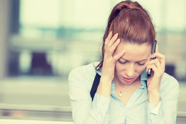 A concerned woman talking on her phone, looking stressed or troubled.