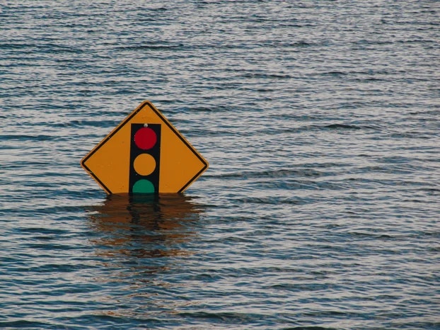 Submerged traffic signal sign in water, possibly due to a flood.