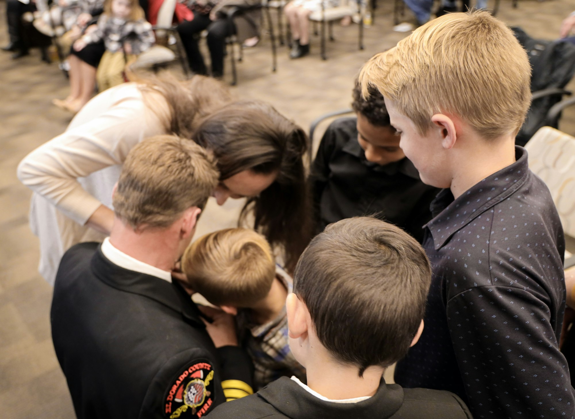 A group of children and adults are gathered, focused on something important, possibly during a ceremony or celebration.