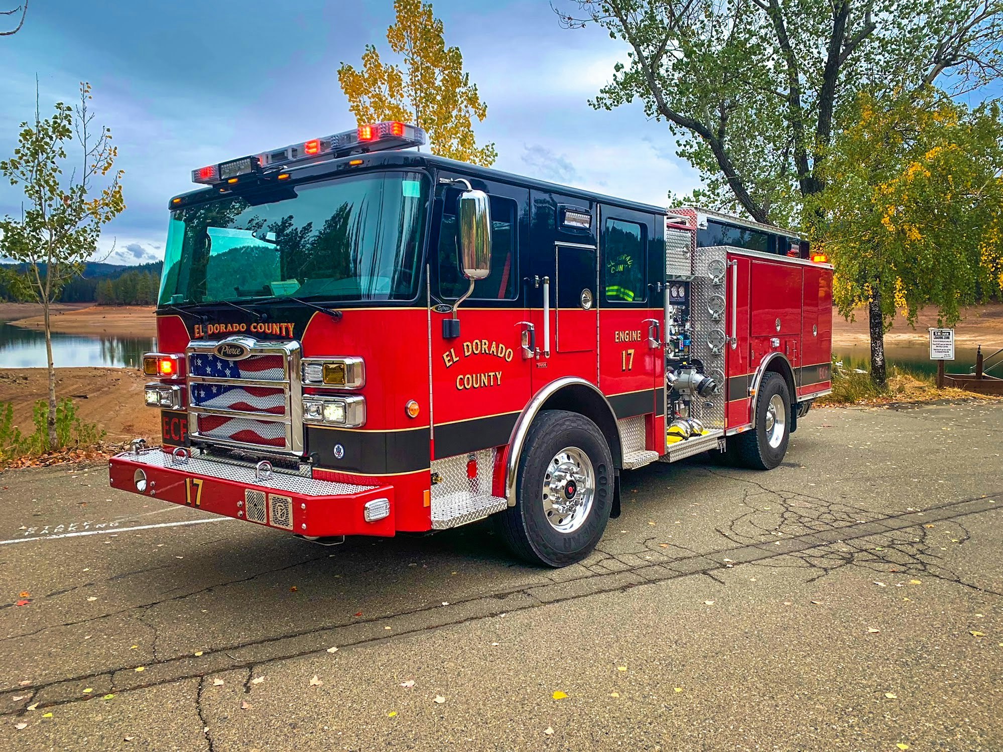 The image features a red fire engine, labeled "El Dorado County Engine 17," parked near a serene body of water and trees.