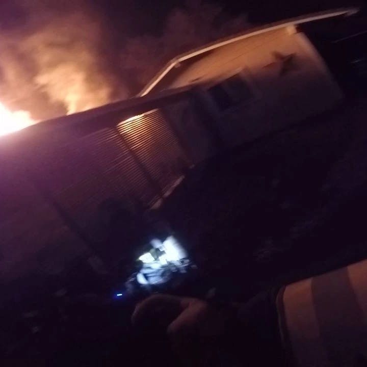 contains dark house, flames and smoke coming from roof, firefighter's hand holding thermal camera screen