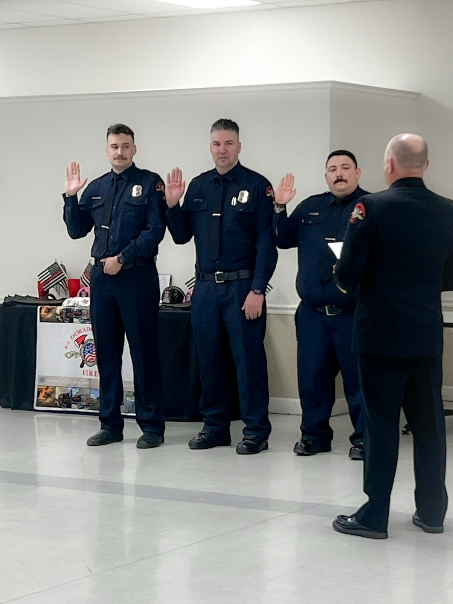 Three uniformed personnel taking an oath with a fourth person facing them, likely in a formal ceremony.