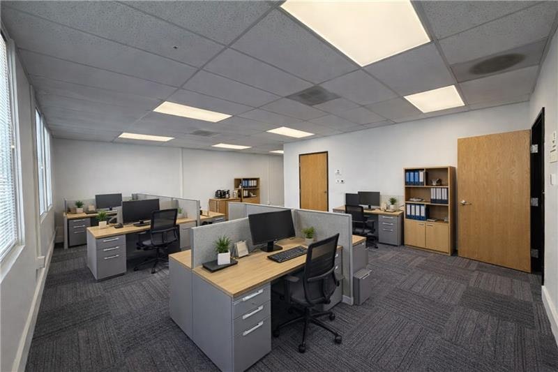 Modern office space with multiple desks, computers, and filing cabinets, featuring a bright and organized layout.