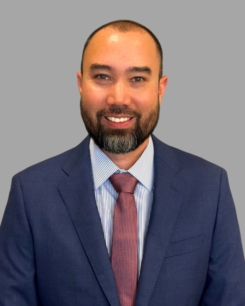A smiling man in a suit with a striped shirt and tie.