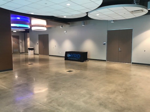 Spacious room with polished floors, modern ceiling lights, doors, and a table with "WRD" logo.