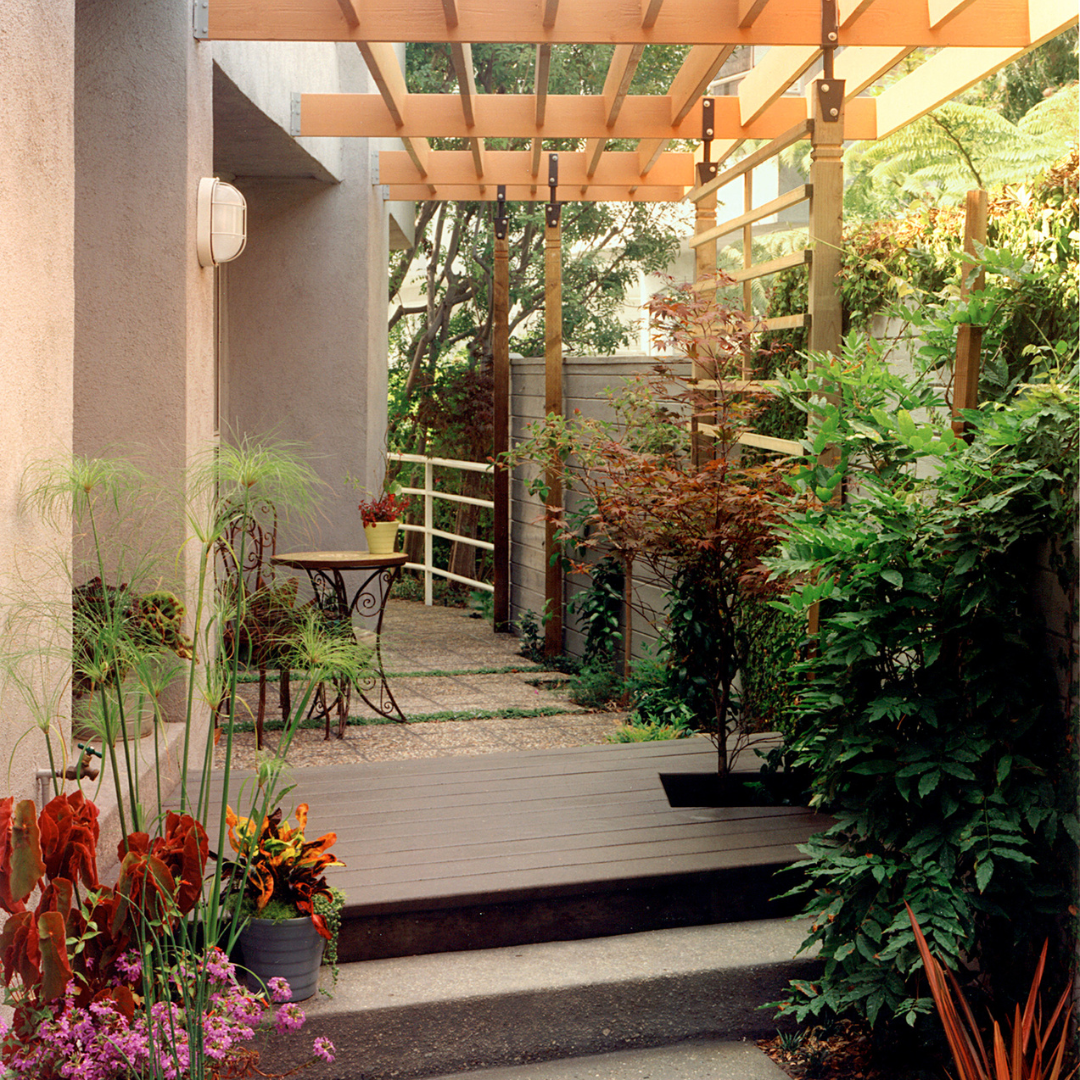 Tranquil garden patio with plants, wooden pergola, and a bistro table set.