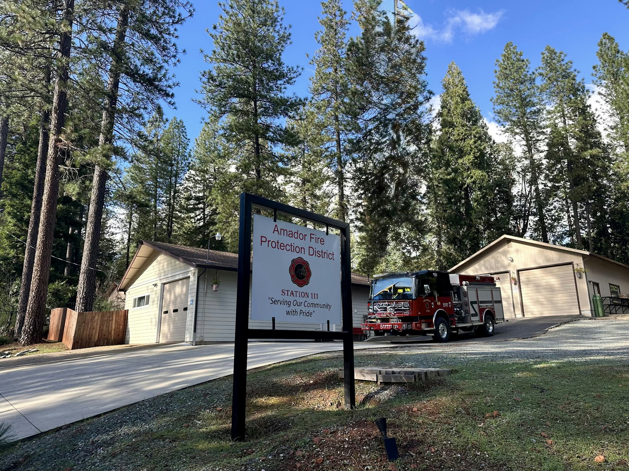 A fire station for the Amador Fire Protection District, featuring a fire truck and surrounded by pine trees.