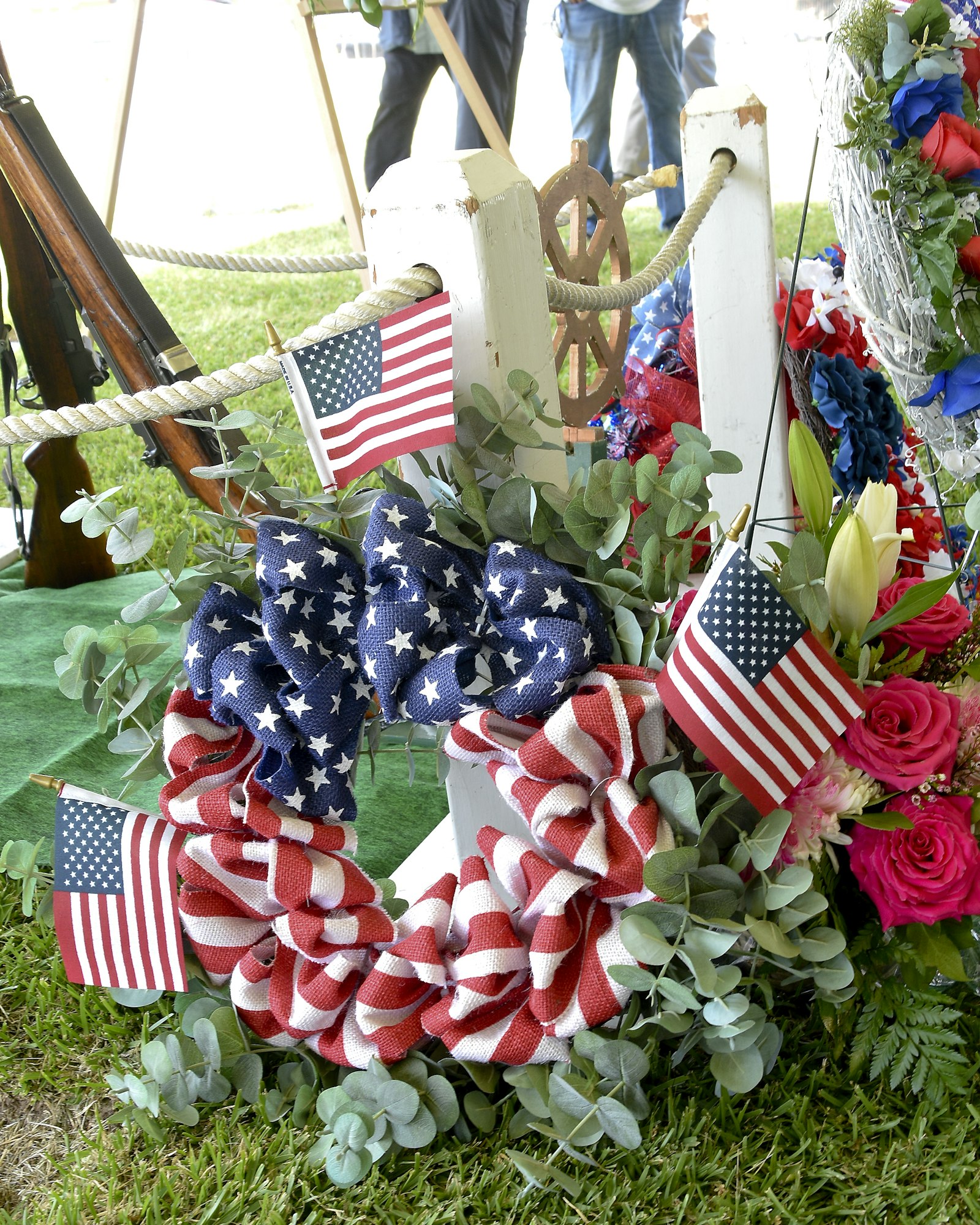 A patriotic wreath with American flags surrounded by flowers and nautical decor.
