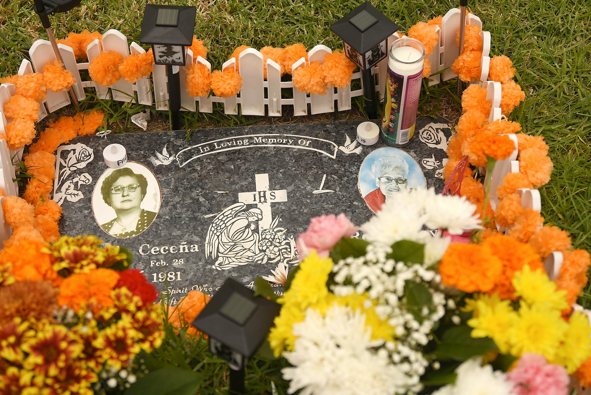 A decorated grave with flowers, photos, and candles, likely commemorating a loved one.