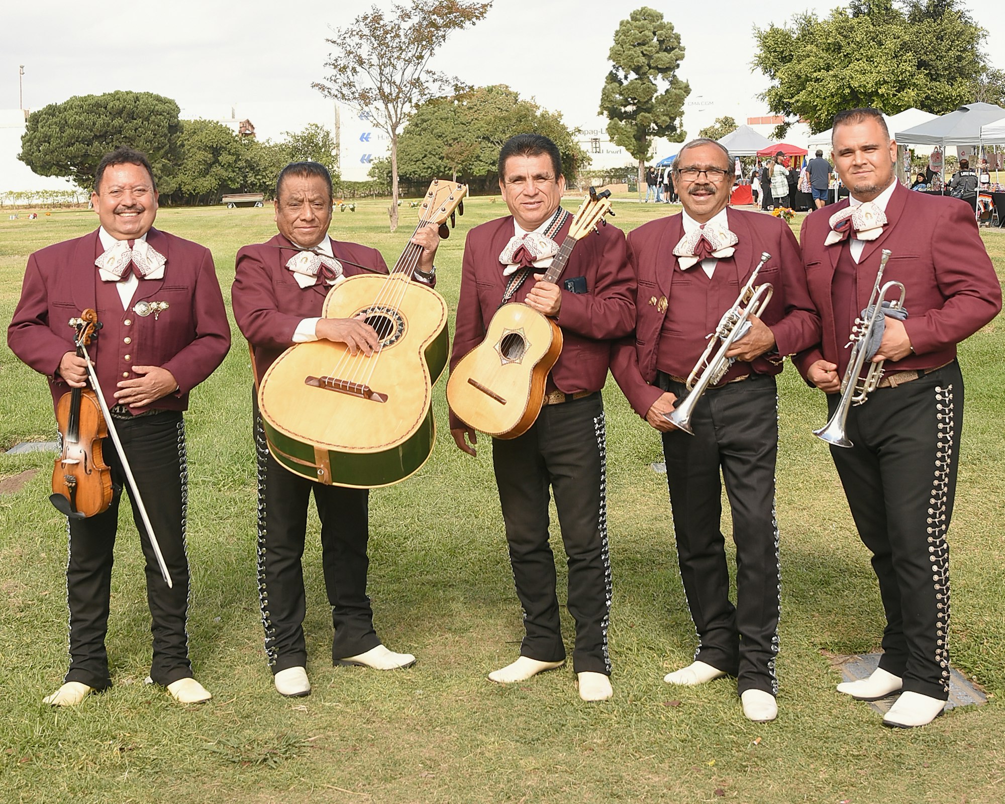 A mariachi band with violins, guitars, and trumpets, dressed in traditional attire.