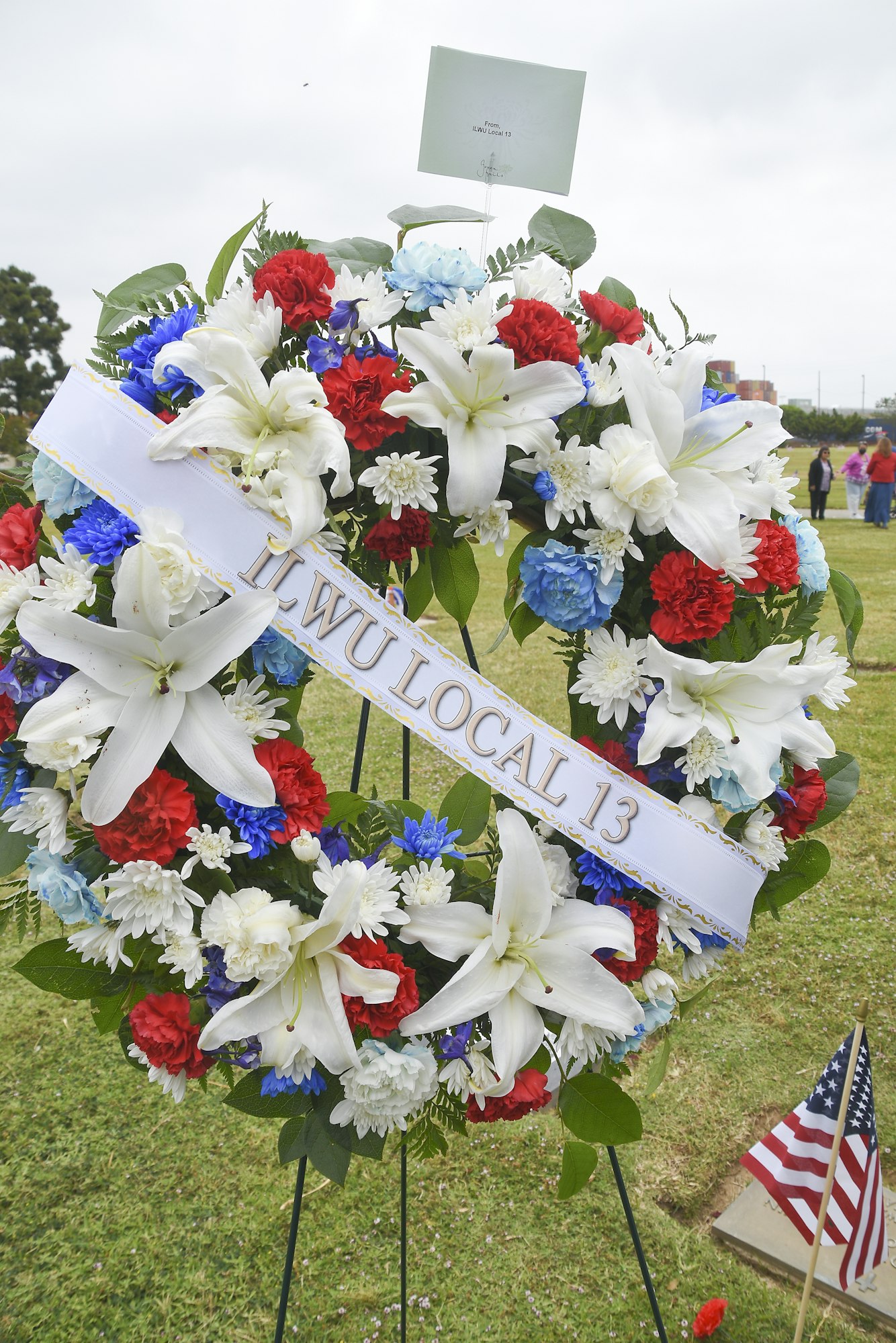 A floral wreath with a ribbon reading "ILWU LOCAL 13" and an American flag, likely a tribute or memorial.