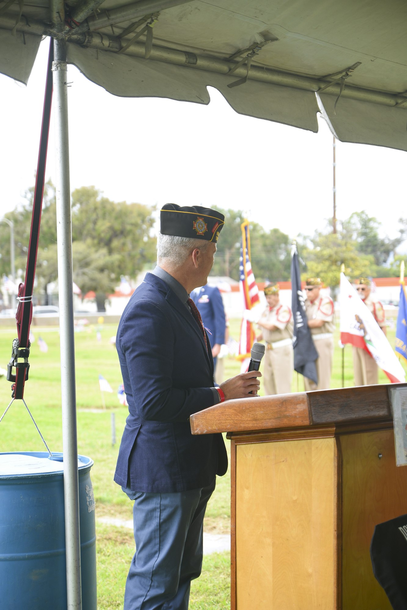 May contain: plywood, wood, adult, male, man, person, captain, officer, clothing, hat, electrical device, microphone, glove, accessories, formal wear, tie, and crowd