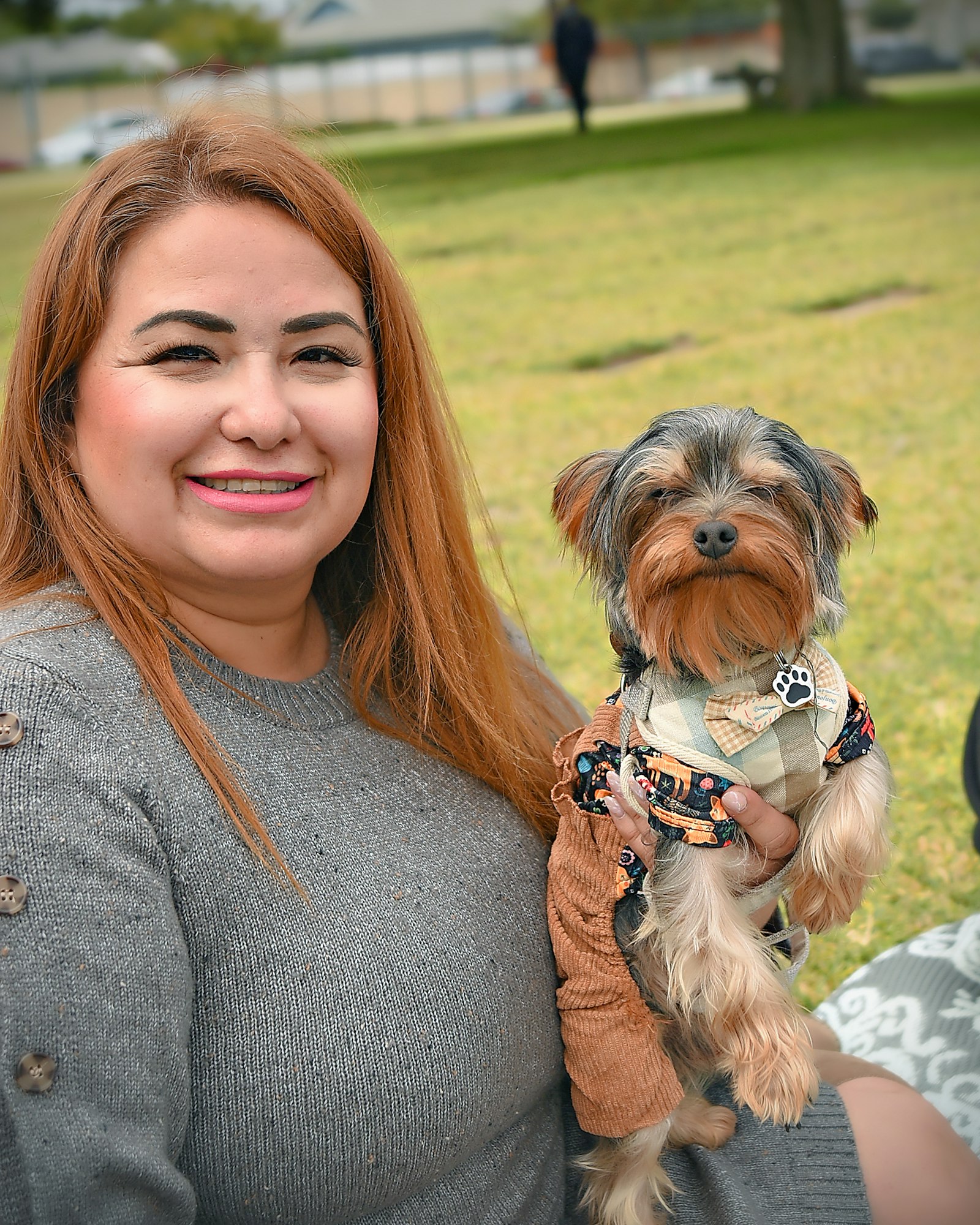 A woman holding a small dog in a park.